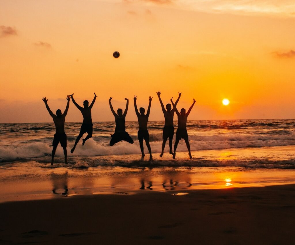 time lapse photography of group of people jumping on seashore under golden hour