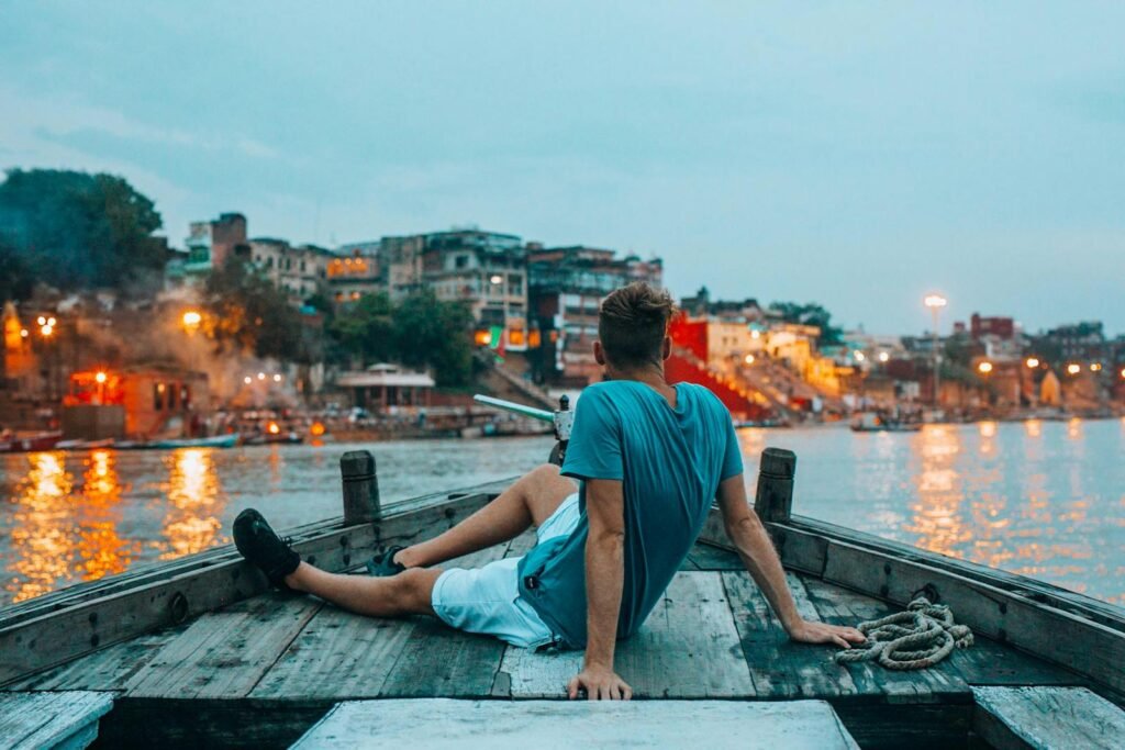Man enjoying a scenic boat ride on the Ganges River in Varanasi, India at sunset.